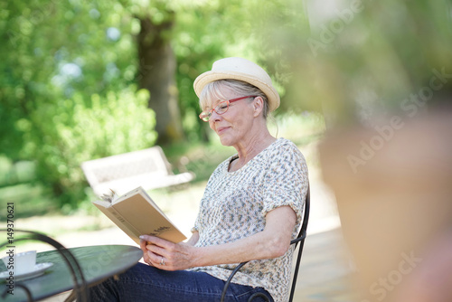 Senior woman relaxing in garden and reading book