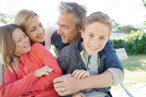 Portrait of happy family of four sitting on bench © goodluz