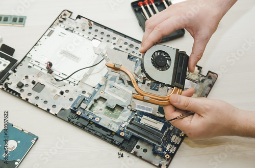 Repair laptops, close-up of hands and dismantled old computer. © natavilman