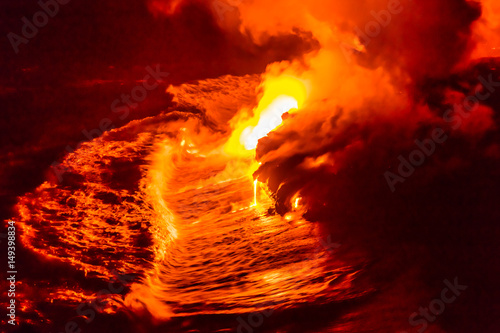 Lava flow pouring into Hawaii ocean at night. Lava falling in ocean waves in Hawaii from Hawaiian Kilauea volcano at night. Molten lava washed by the pacific ocean water crashing in, Big Island, USA. © Maridav