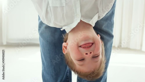 father holding son upside down, he's having fun and smiling