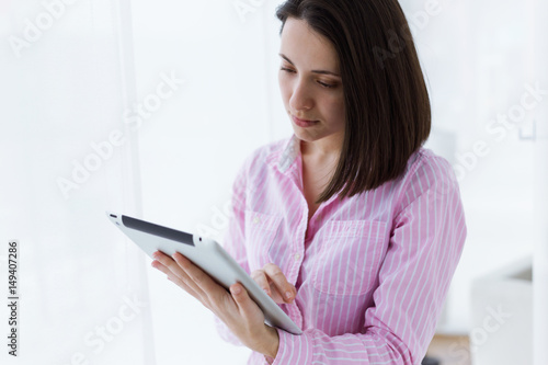 Beautiful young woman using her digital tablet in the office.