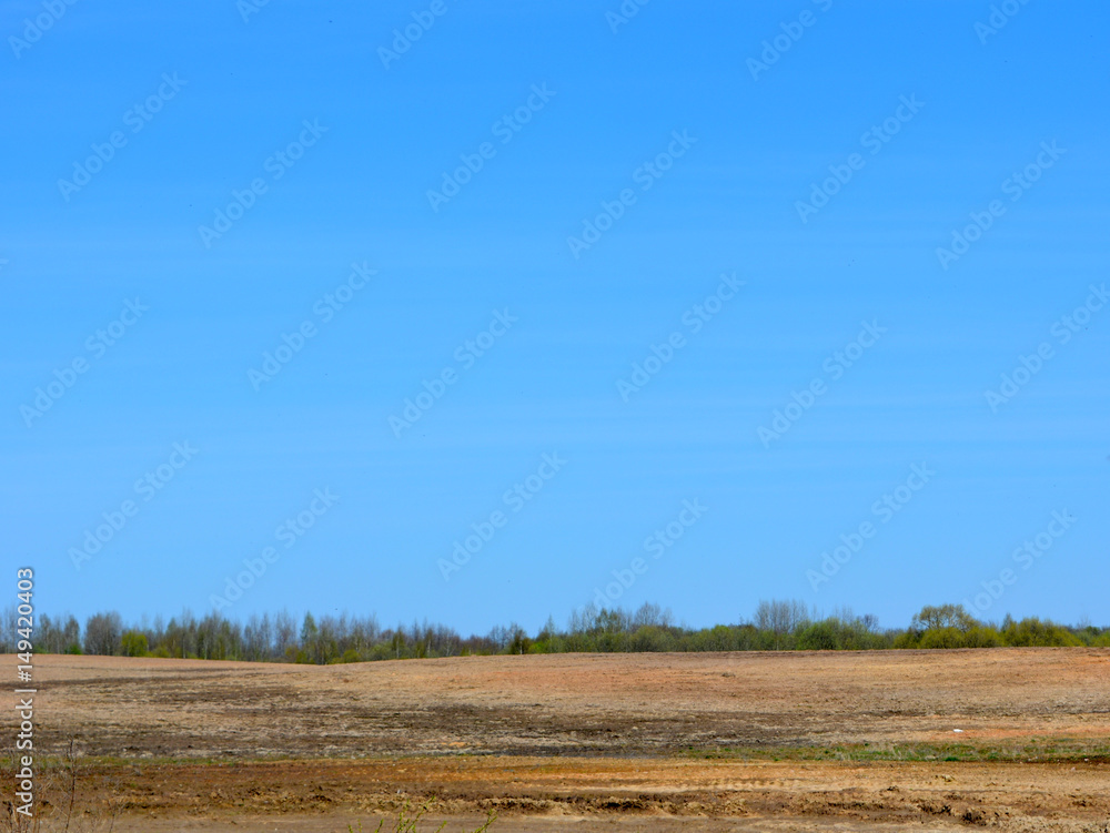 Plowed field against the blue sky, beautiful spring landscape 