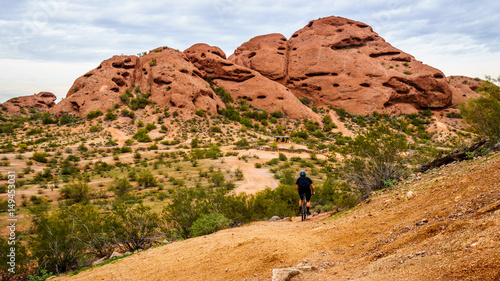 Biking down the red sandstone buttes of Papago Park, with its many caves and crevasses caused by erosion under cloudy sky, in the city of Tempe, Arizona in the United States of America