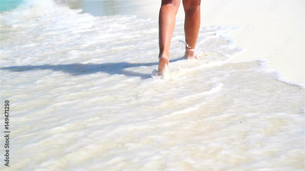 Close-up legs running along the white beach in shallow water. Concept of beach vacation and barefoot. SLOW MOTION. Close-up legs running along the white beach in shallow water. Concept of beach vacation and barefoot. SLOW MOTION.