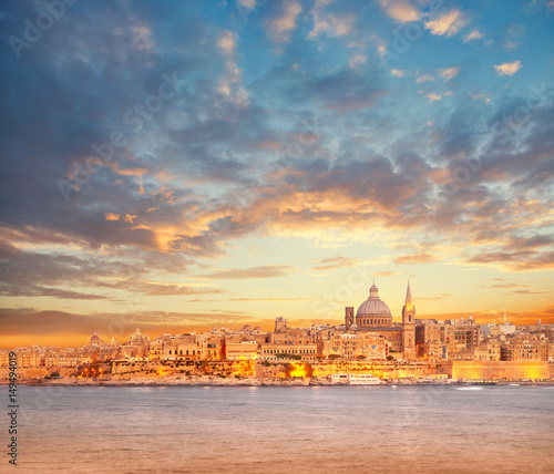 Beautiful spires and cathedral dome of Valletta under dramatic sky on the sunset photo