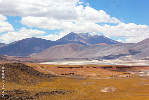 Volcanic mountains landscape of Atacama Desert, Chile. Colorful salt flats and mountains on horizon under white clouds.