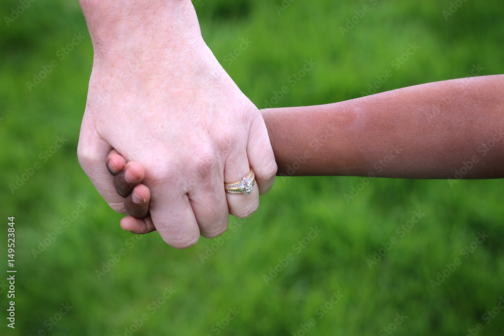An African child holding his caucasian adoptive mother's hand. An African child holding his caucasian adoptive mother's hand.