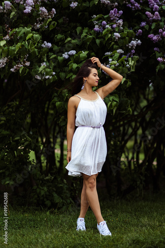 beautiful young woman in a summer dress near blooming lilac