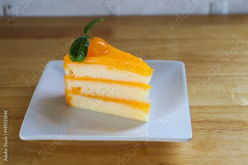 Piece of Orange cake on wooden table. photo