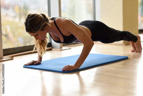 Young beautiful woman doin pushups in the gym.
