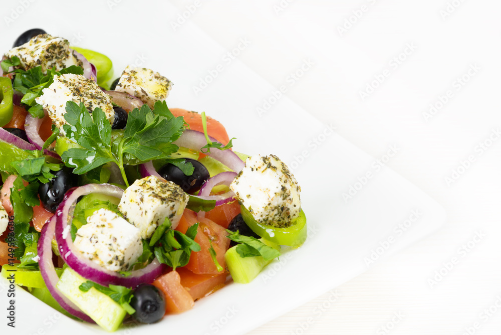Greek salad with fresh tomato, cucumber, red onion, basil, feta cheese, black olives, Italian herbs and olive oil in white dish on white wooden table. Greek salad with fresh tomato, cucumber, red onion, basil, feta cheese, black olives, Italian herbs and olive oil in white dish on white wooden table.
