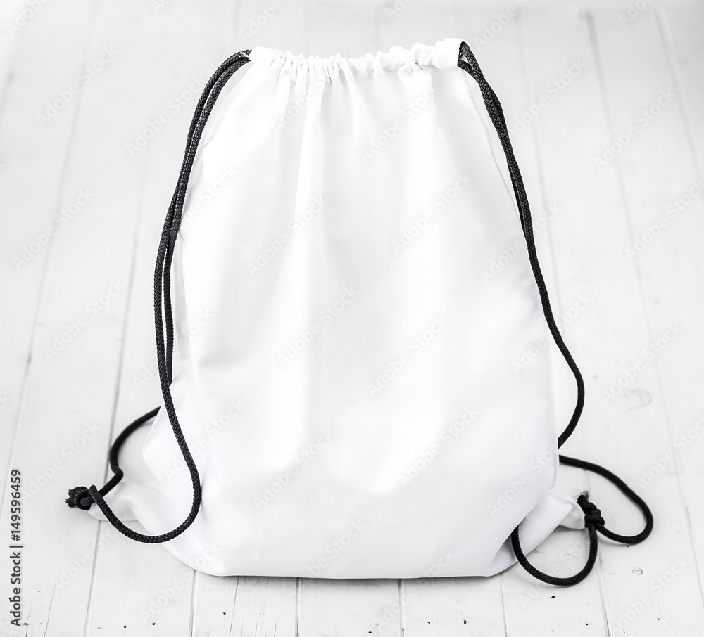white backpack with black string on planked surface - obrazy, fototapety, plakaty 