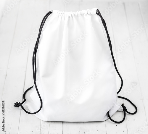 white backpack with black string on planked surface