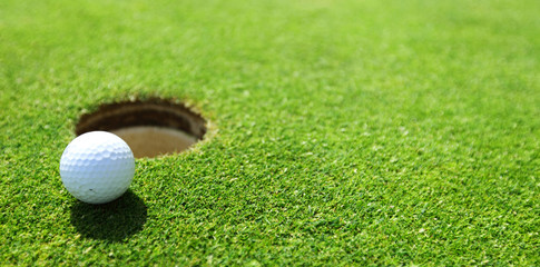 Acrylglasbilder Golf Golfball am Lochrand auf dem Grün  © yellowj
