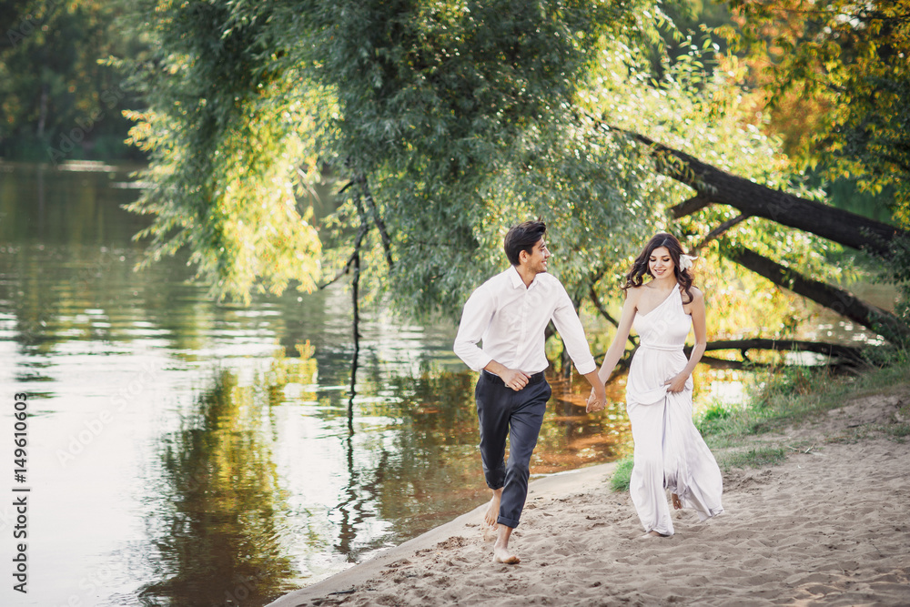 The bride and groom running along the sandy shore. The bride and groom running along the sandy shore.