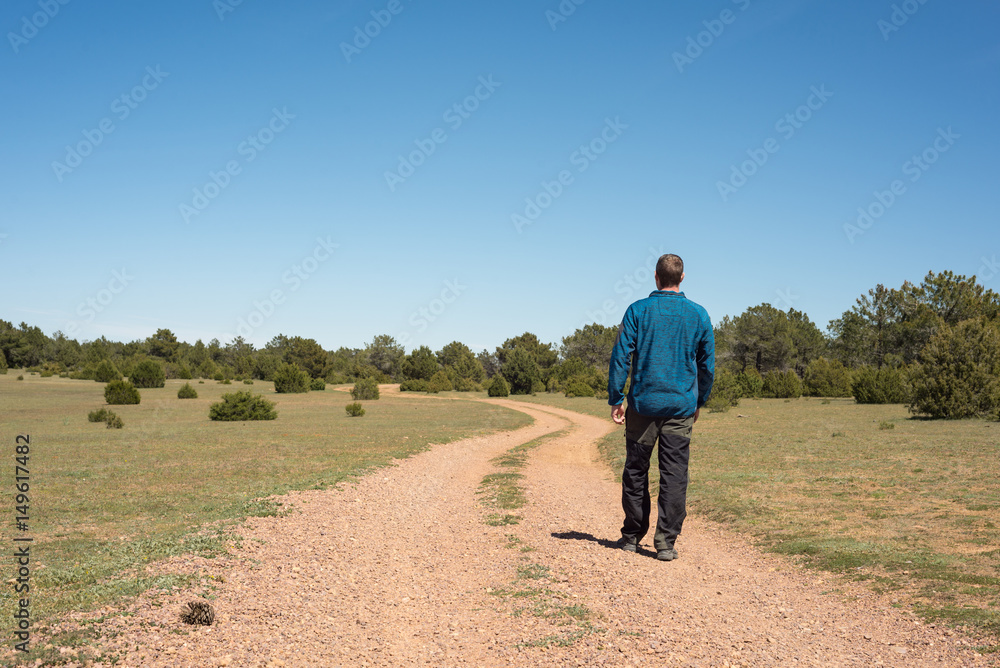 Hombre joven andando sobre un camino serpenteante Hombre joven andando sobre un camino serpenteante