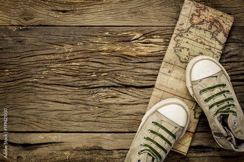 Top view essential travel items.The man shoes and vintage map on old rustic wooden background with copy space.