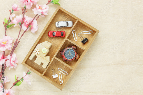 Top view business office desk concept. Wood house also car and clock on wooden shelf.The beautiful pink flower on wood background with copy space.