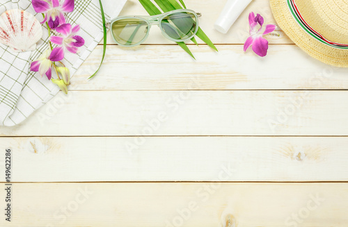 Top view essential travel summer items.The sunblock moisturizing  hat  sunglasses orchid on white  wooden background.
