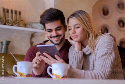 Loving couple sitting in the cafe, drinking tea and having fun with tablet. Love, romance, dating, lifestyle, relationships