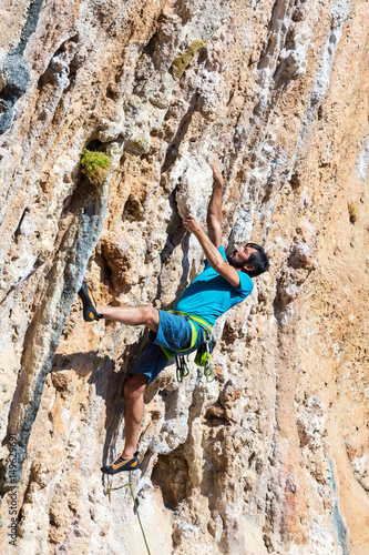 Mature male Climber hanging on dangerous Rock