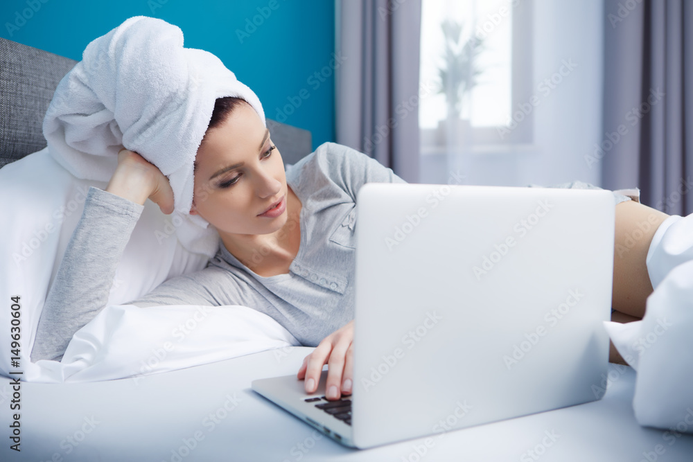 smiley young woman lying in her bed with laptop smiley young woman lying in her bed with laptop