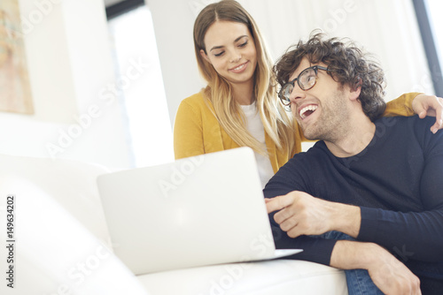Shopping online. Shot of a lovely young couple relaxing on the couch and using a laptop at home © gzorgz