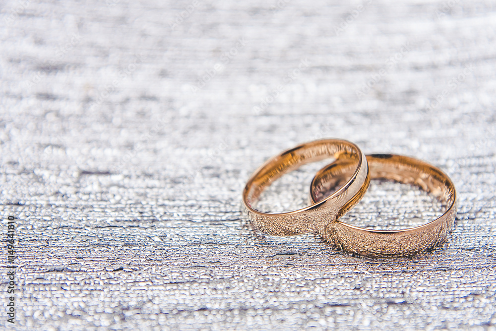 Two golden wedding rings on diamond shiny plate. Two golden wedding rings on diamond shiny plate.