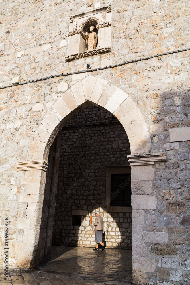 An old woman passes an archway