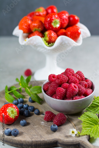 Fresh organic summer berries - ripe raspberry  strawberry  blueberry with leaves on wood background