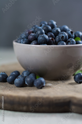 Freshly picked juicy blueberries with green leaves on rustic table. Bilberry on wooden Background. Blueberry antioxidant. Concept for healthy eating and nutrition