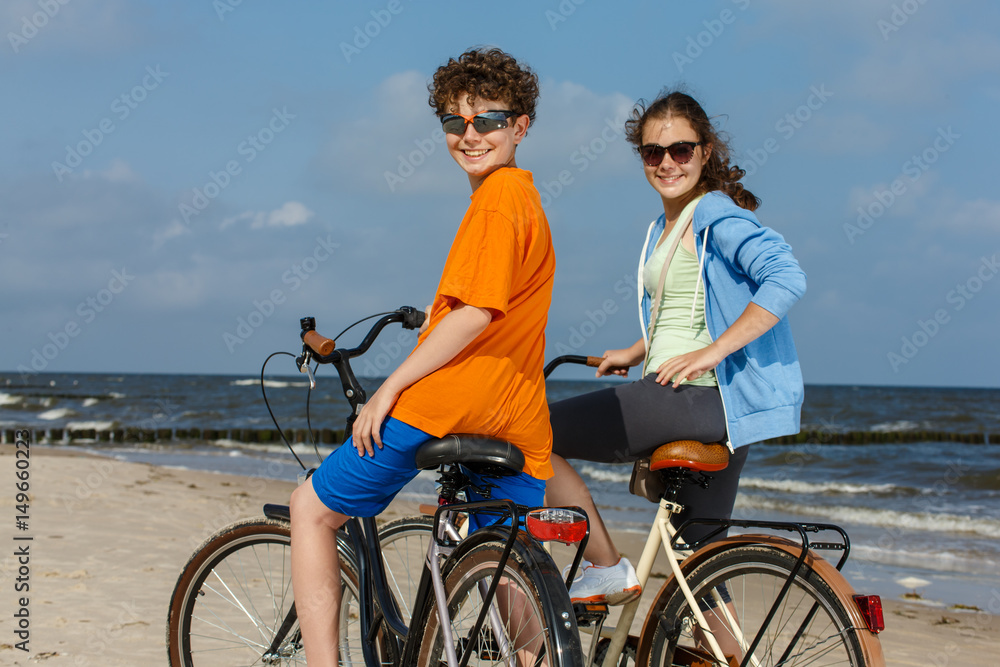 Teenage girl and boy biking on beach