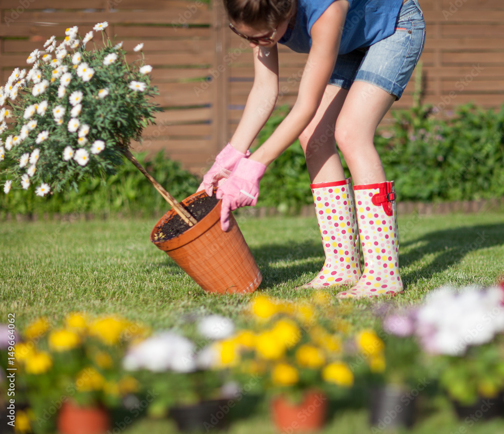Φωτογραφία Woman wearing gloves and wellington boots holding pot with a daisy flower