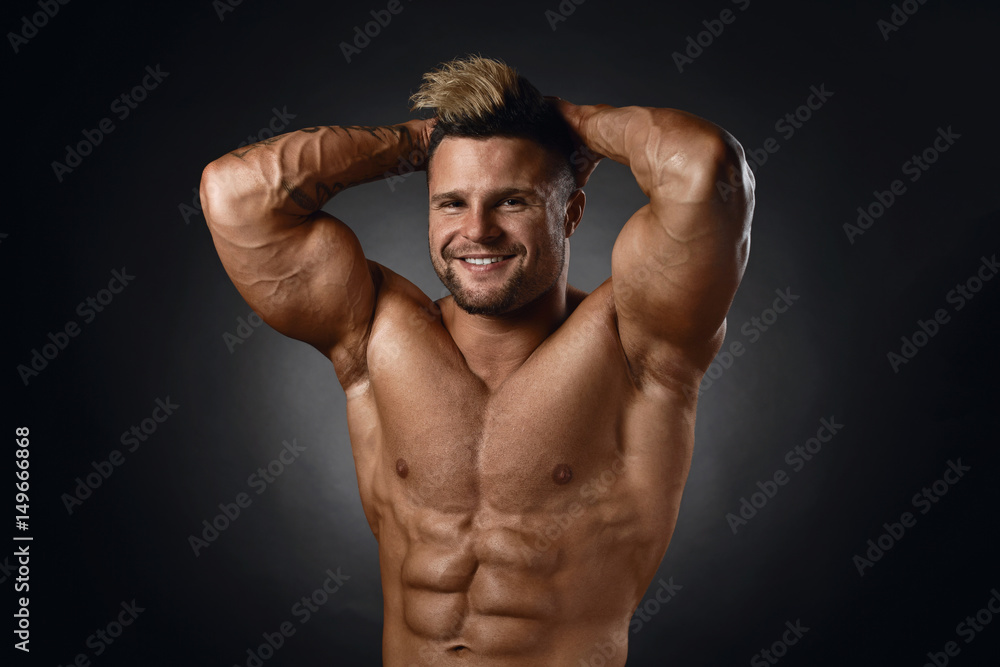 Studio portrait of topless muscular sportsman smiling over black background Studio portrait of topless muscular sportsman smiling over black background