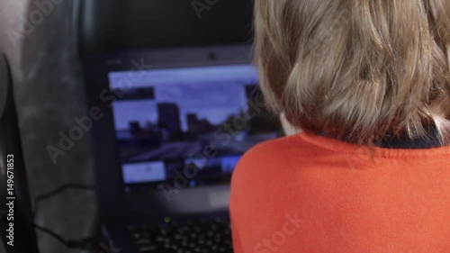 Close up of a little boy sitting on the floor and trying to learn with a computer. New generation and technology concept. photo