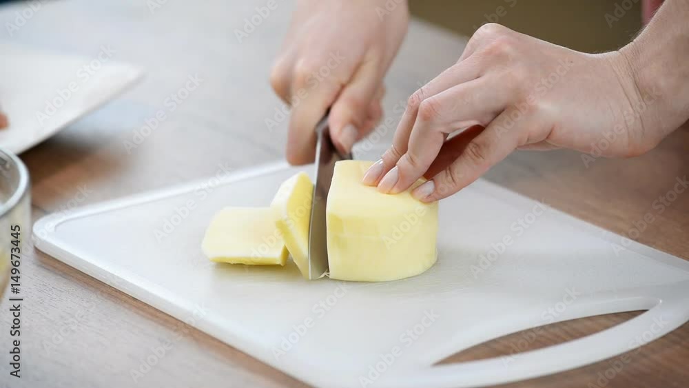 Female hands cutting mozzarella cheese on the wooden cutting board Female hands cutting mozzarella cheese on the wooden cutting board