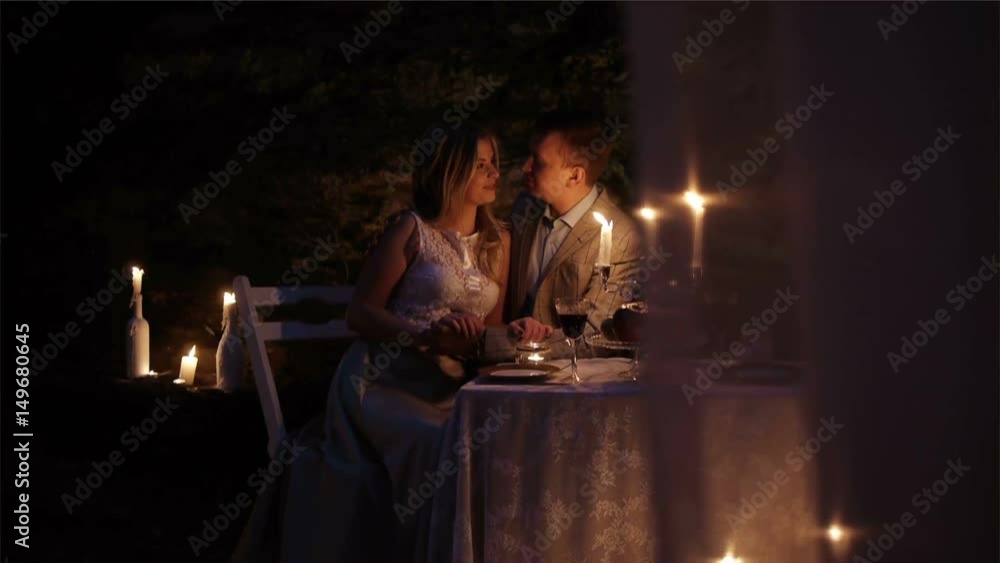 A couple on a romantic date, sitting at a beautifully laid table in the evening outdoors. Candlelight dinner A couple on a romantic date, sitting at a beautifully laid table in the evening outdoors. Candlelight dinner