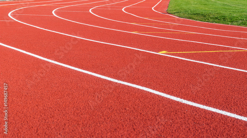 Red running track and white lanes on sport stadium