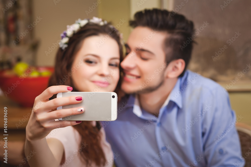Young enamored couple sitting at a table in a cafe and making selfie Young enamored couple sitting at a table in a cafe and making selfie
