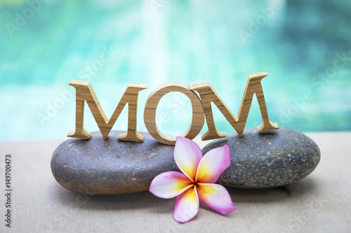 Mother's day concept background, mom wooden text on spa stone with space on blurred swimming pool background