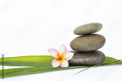 Zen stone on green bamboo leaf and flower on white background, spa concept background