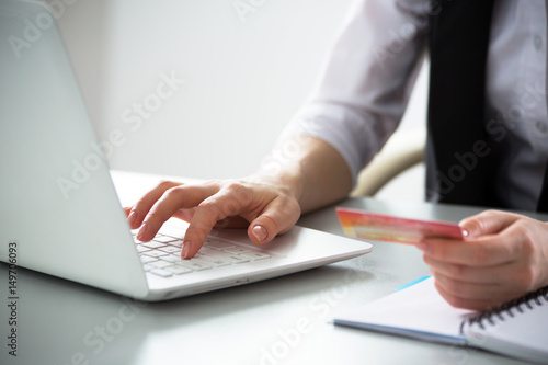 Business woman holding credit card and using laptop.