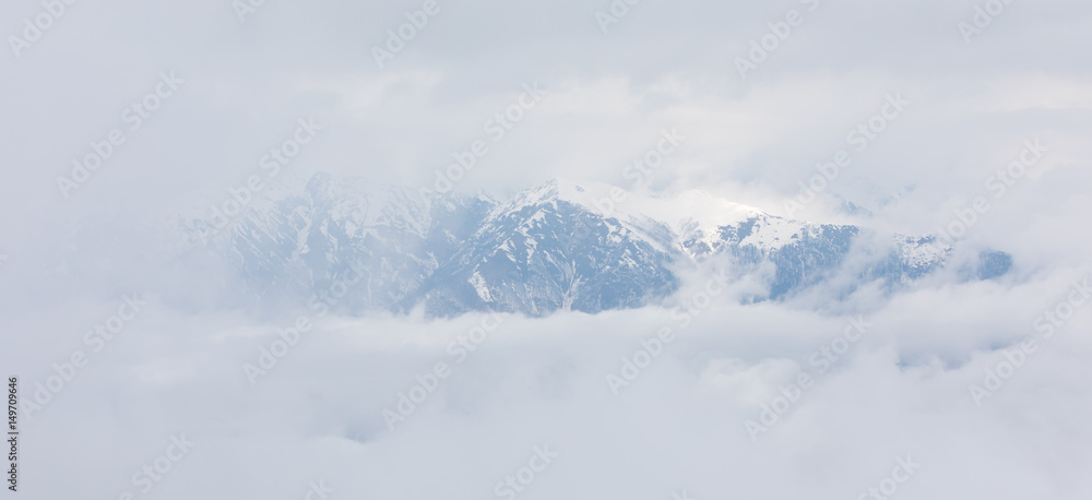 Mountain with snow in the clouds with a backlight from the sunlight