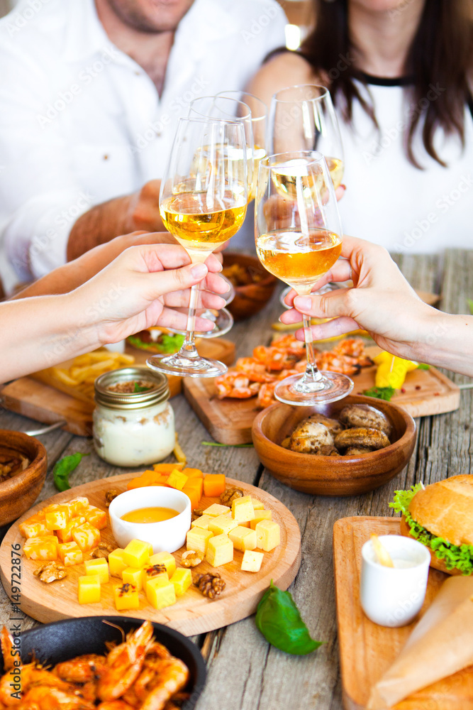 Hands with red wine toasting over served table with food. Hands with red wine toasting over served table with food.