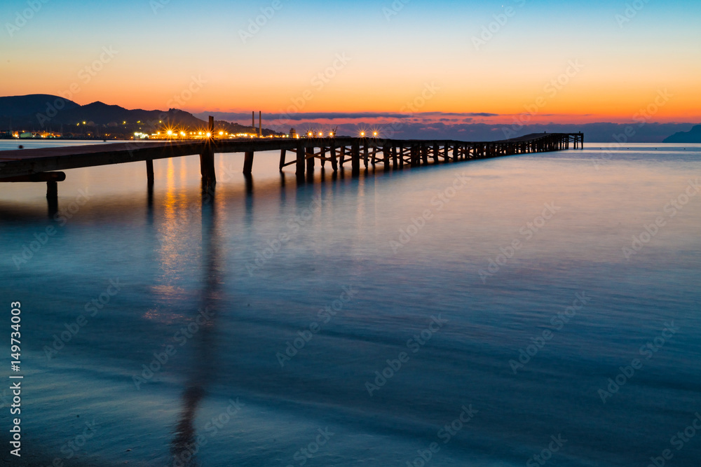 Sunset on a sandy beach and a wooden pier, Panorama