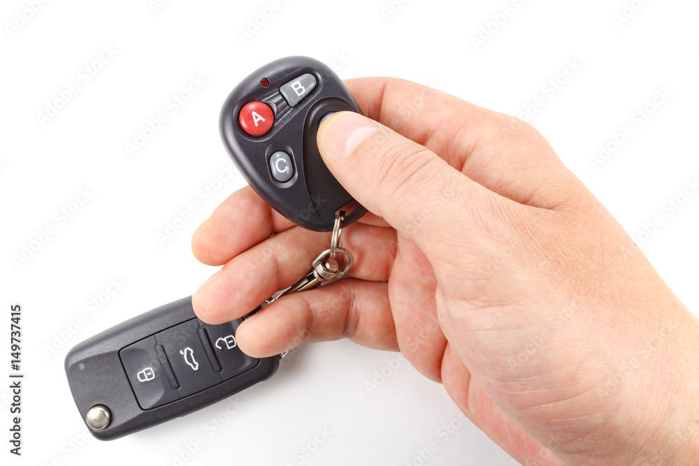 Man presses button on the garage door remote control on a white background Man presses button on the garage door remote control on a white background