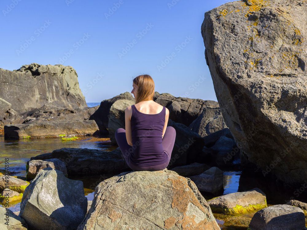 Girl practices yoga near the sea, on the rock, slow motion hd video