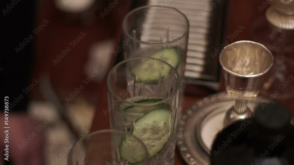 Bartender puts a slice of cucumber in glass. Cocktail preparation in bar with cucumber Bartender puts a slice of cucumber in glass. Cocktail preparation in bar with cucumber
