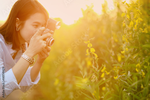 Beautiful woman hand holding a camera on field in summer soft  spring sunset